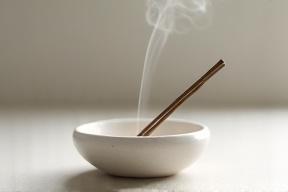 Elegant handmade ceramic incense holder with a single burning incense stick.