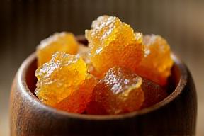 Glistening chunks of various natural resin incense in a small wooden bowl.